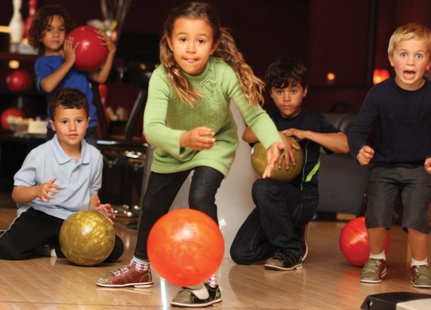 Birthday child bowling while everybody else watches